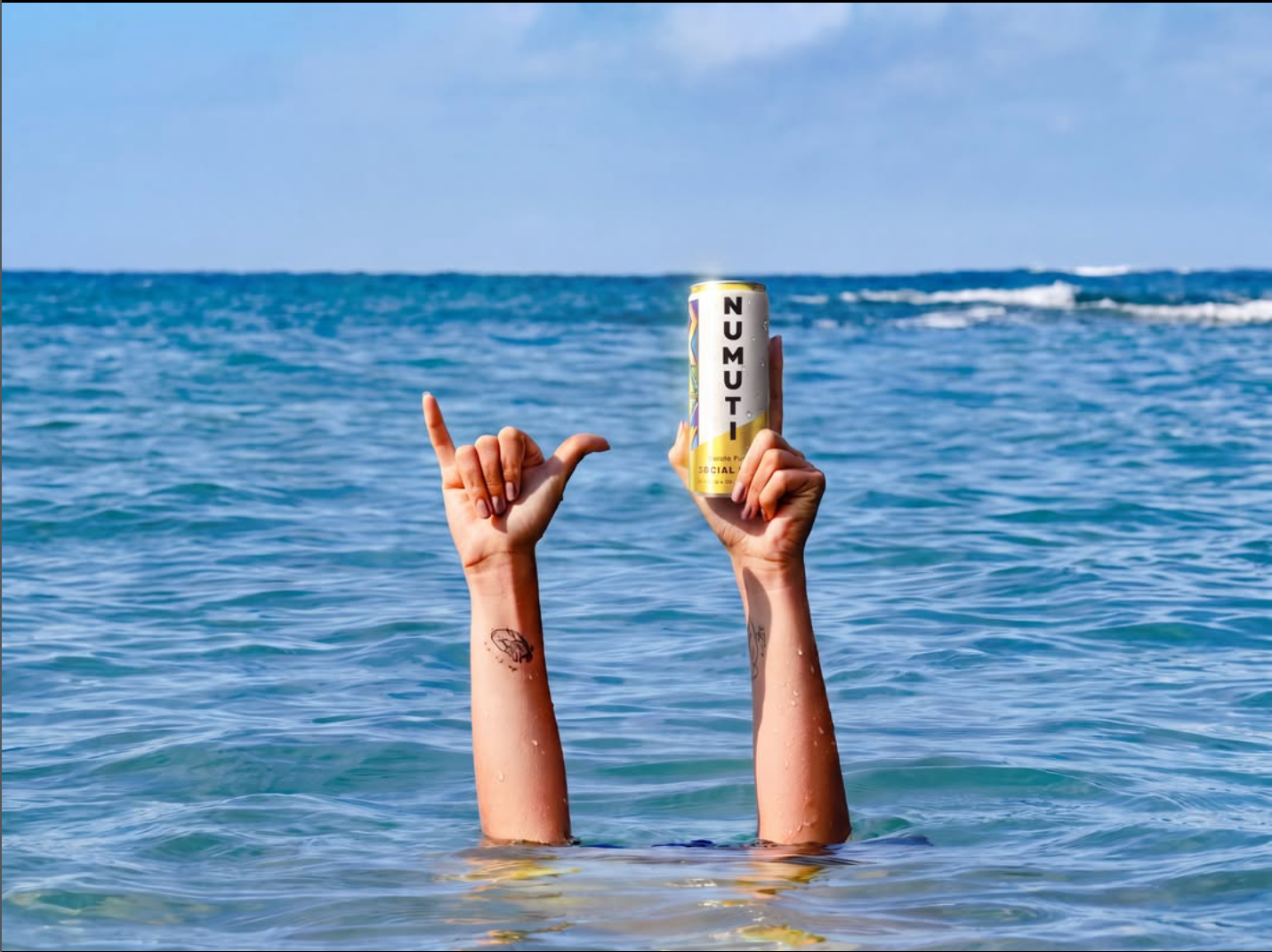 Marula can held above the ocean beside a raised hand