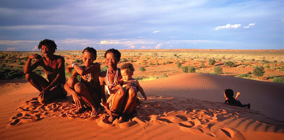 A group sitting together on sunlit red sand dunes